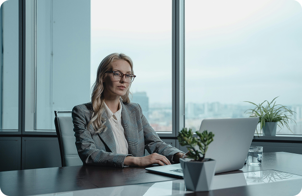 Femme assise à un bureau en train de regarder son ordinateur