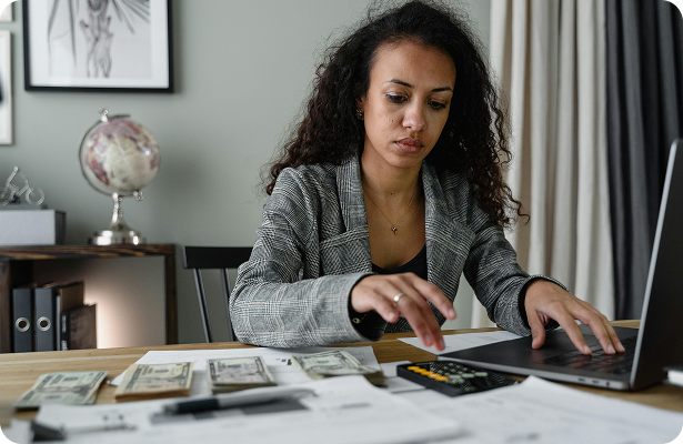 Image d'une femme faisant ses comptes devant son ordinateur