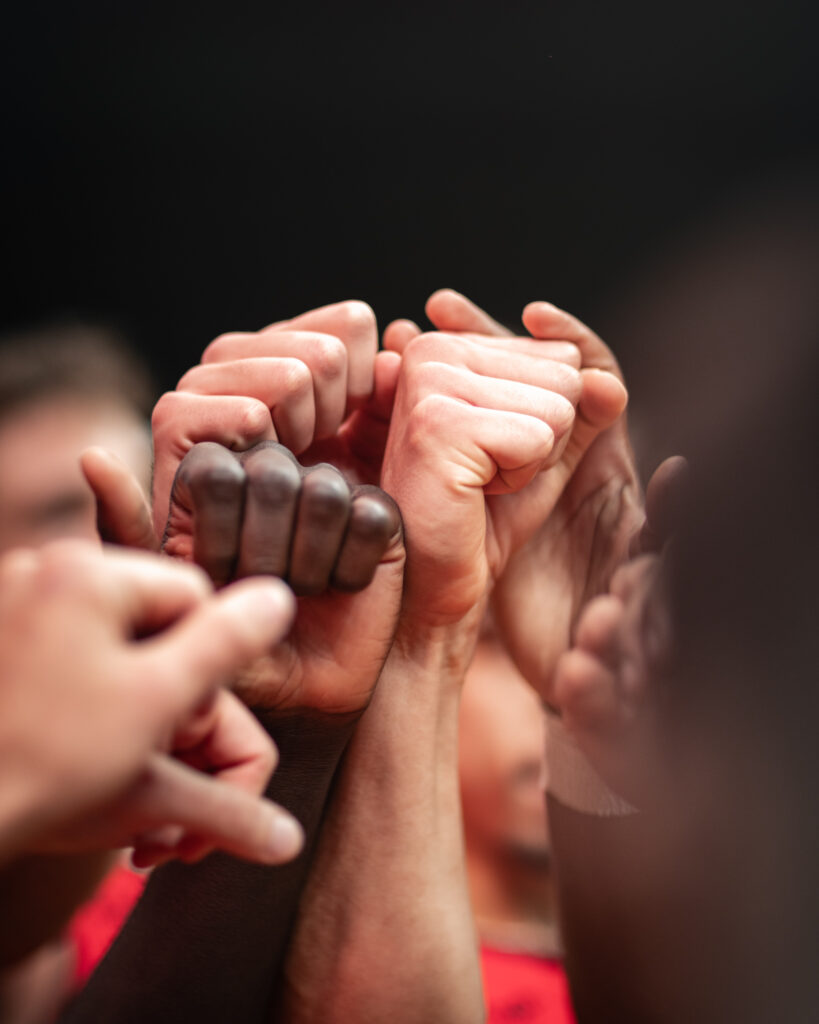 Image de poings levés pour célébrer une victoire. Différentes couleurs de peau sont visibles